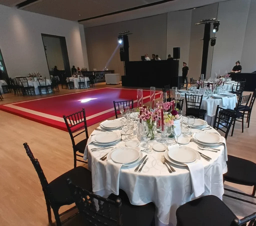 Salón-de-eventos-con-mesa-montada-escenario-e-iluminación